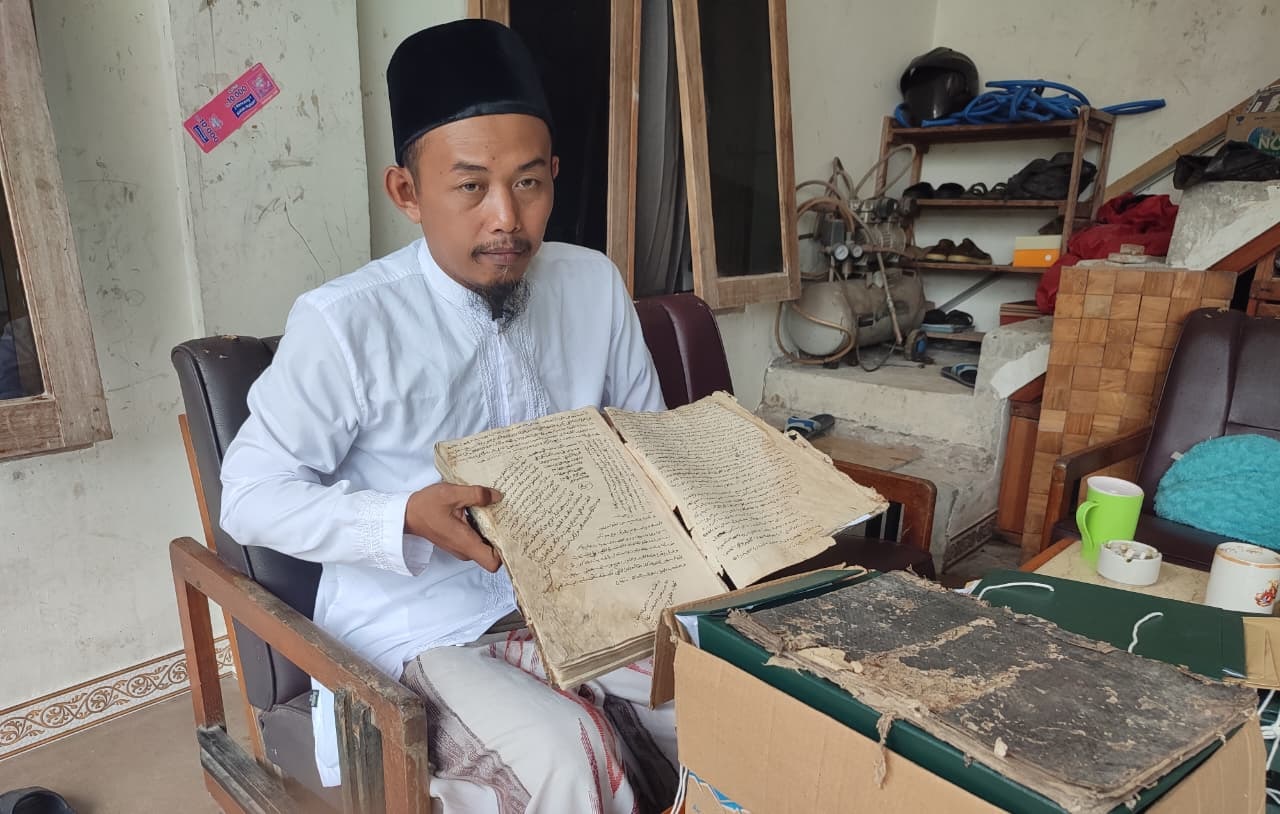 MA. Ghufron Zamroni, generasi keenam KH Abu Ishaq Madyani saat menunjukkan kitab dan manuskrip peninggalan KH Abu Ishaq Madyani.