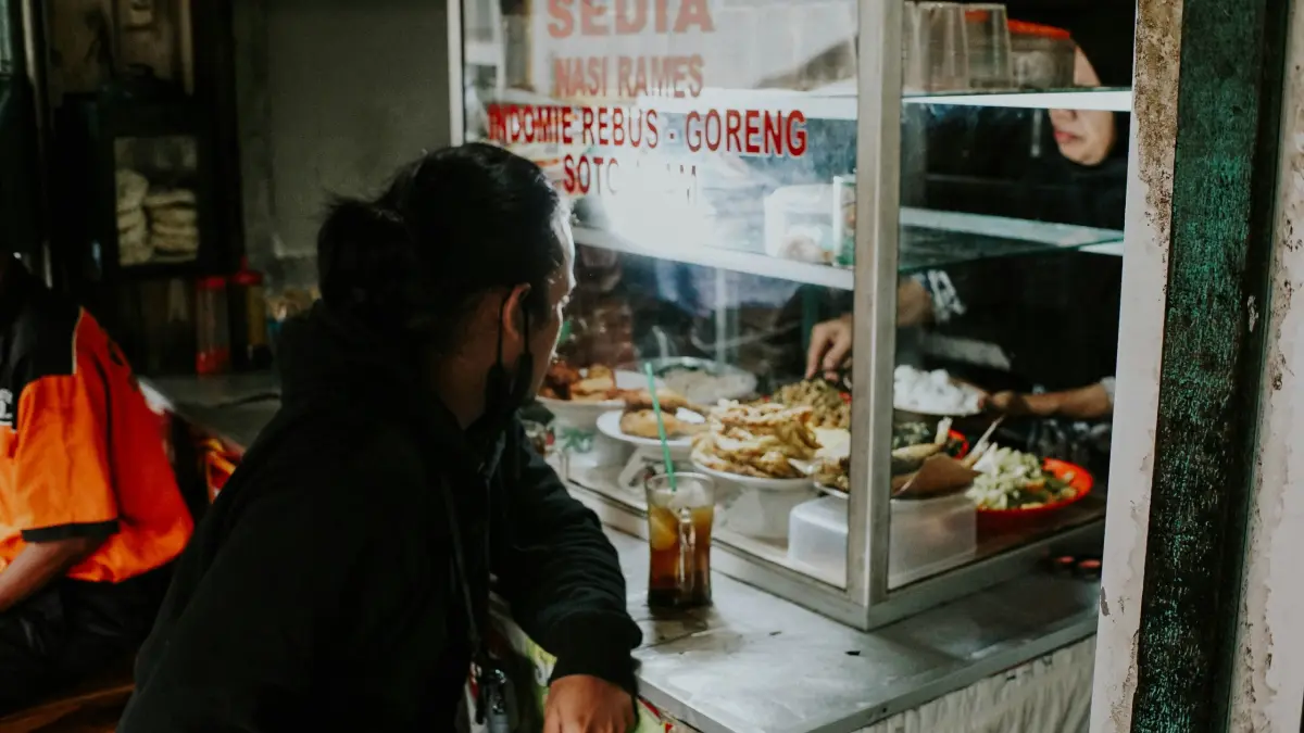Pedagang warteg terpaksa mengurangi takaran porsi makan demi menyiasati lonjakan harga bahan pokok yang kian mencekik. (Unsplash / Falaq Lazuardi)