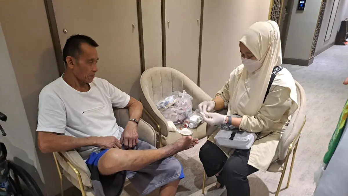 Eni Rahmawati, paramedis dari kloter 29 Sub Embarkasi Surabaya merawat luka pada kaki Sakur Rais.