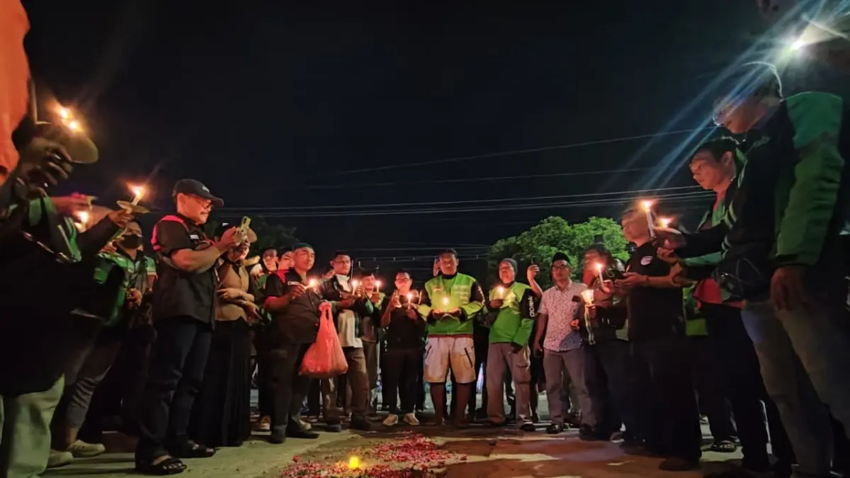Puluhan komunitas ojol Tuban menggelar aksi tabur bunga dan menyalakan lilin di lokasi tewasnya M Iqbal Firmansyah di Jalan Letda Sucipto Tuban depan proyek pembangunan SR Tuban, Rabu (13/5) malam. (ANDREYAN/RADAR TUBAN)