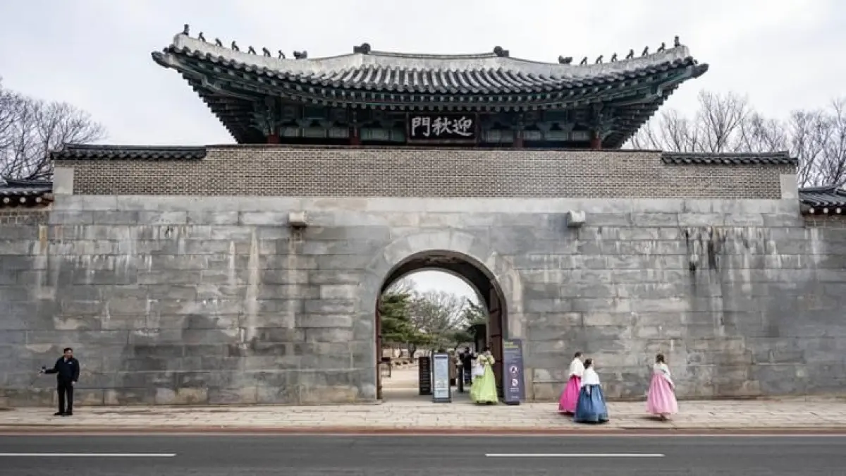 Pengunjung mengenakan hanbok tradisional berjalan melewati gerbang Yeongchumun di Istana Gyeongbokgung, Seoul, Korea Selatan. (JawaPos.com)