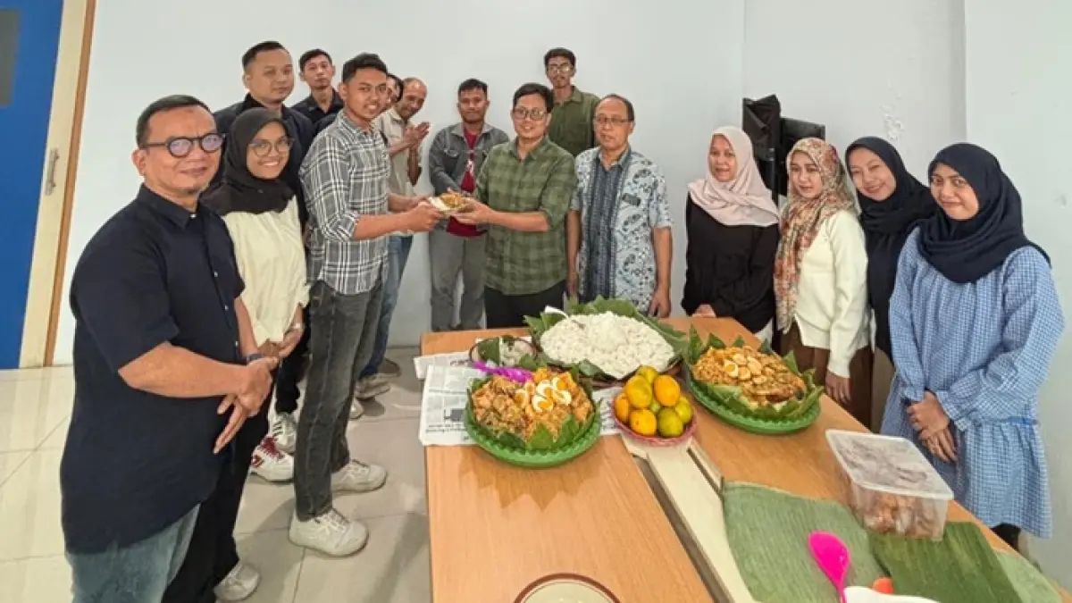 Redaktur Pelaksana Jawa Pos Radar Tuban Ahmad Atho’illah menyerahkan potongan tumpeng kepada karyawan termuda, M. Robit Bilhaq. (SINTA ARISKA/RADAR TUBAN)