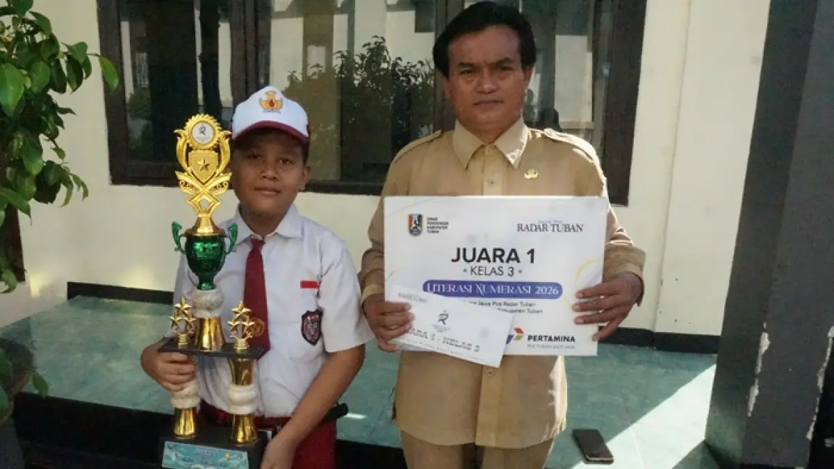Galih memegang pialanya bersama Kepala Sekolah SDN Tenggerkulon setelah penyerahan penghargaan kepada para juara Lomba Literasi-Numerasi, Senin (8/6).&nbsp; (SHAFA DINA HAYUNING MENTARI/RADAR TUBAN)