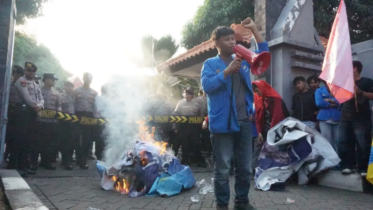Mahasiswa yang mengkritik kebijakan pemerintah yang dinilai tidak prorakyat membakar spanduk di depan aparat keamanan yang berjaga di depan
gedung DPRD Tuban, kemarin (18/6). (SHAFA DINA HAYUNING MENTARI/RADAR TUBAN)