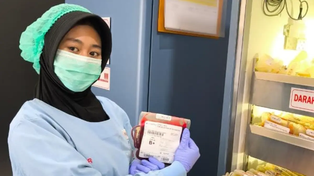 Petugas dengan pakaian steril saat menata kantong darah berdasarkan golongan di lemari pendingin UDD PMI Tuban. (UDD PMI TUBAN UNTUK RADAR TUBAN)