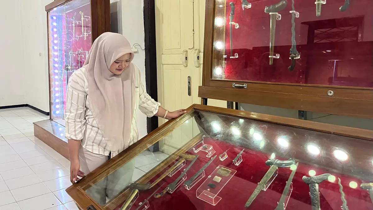 Salah seorang pengunjung Museum Kambang Putih Tuban mengamati koleksi keris di salah satu lemari penyimpanan benda pusaka. (SHAFA DINA MENTARI HAYUNING/RADAR TUBAN)