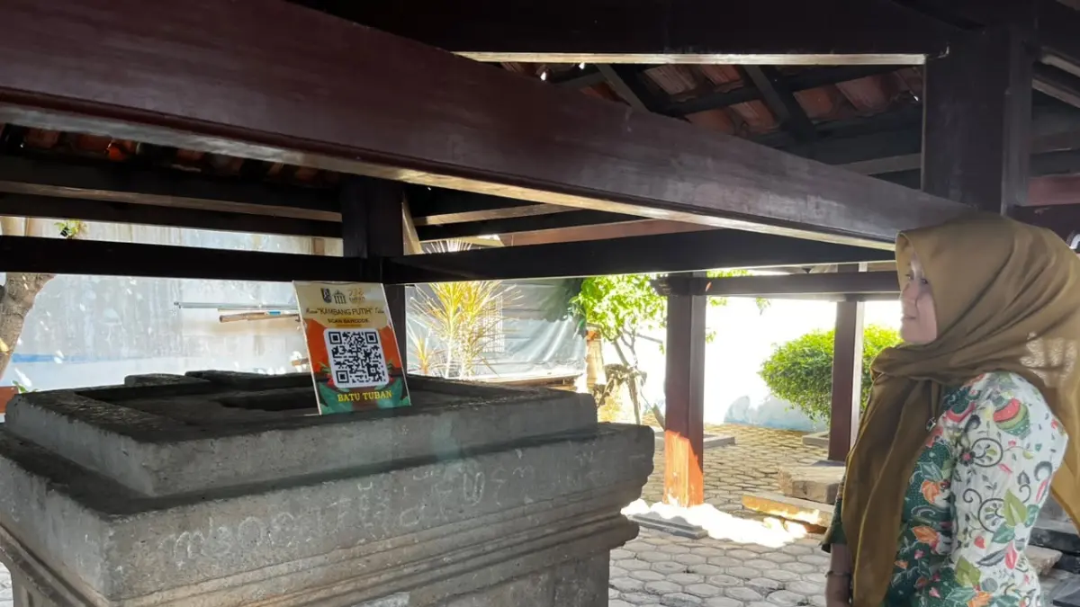 Staf Museum Kambang Putih Tuban menjelaskan batu yoni yang juga disebut Watu Tiban di halaman belakang museum setempat, Jumat (24/7). (Shafa Dina Hayuning Mentari/Radar Tuban)