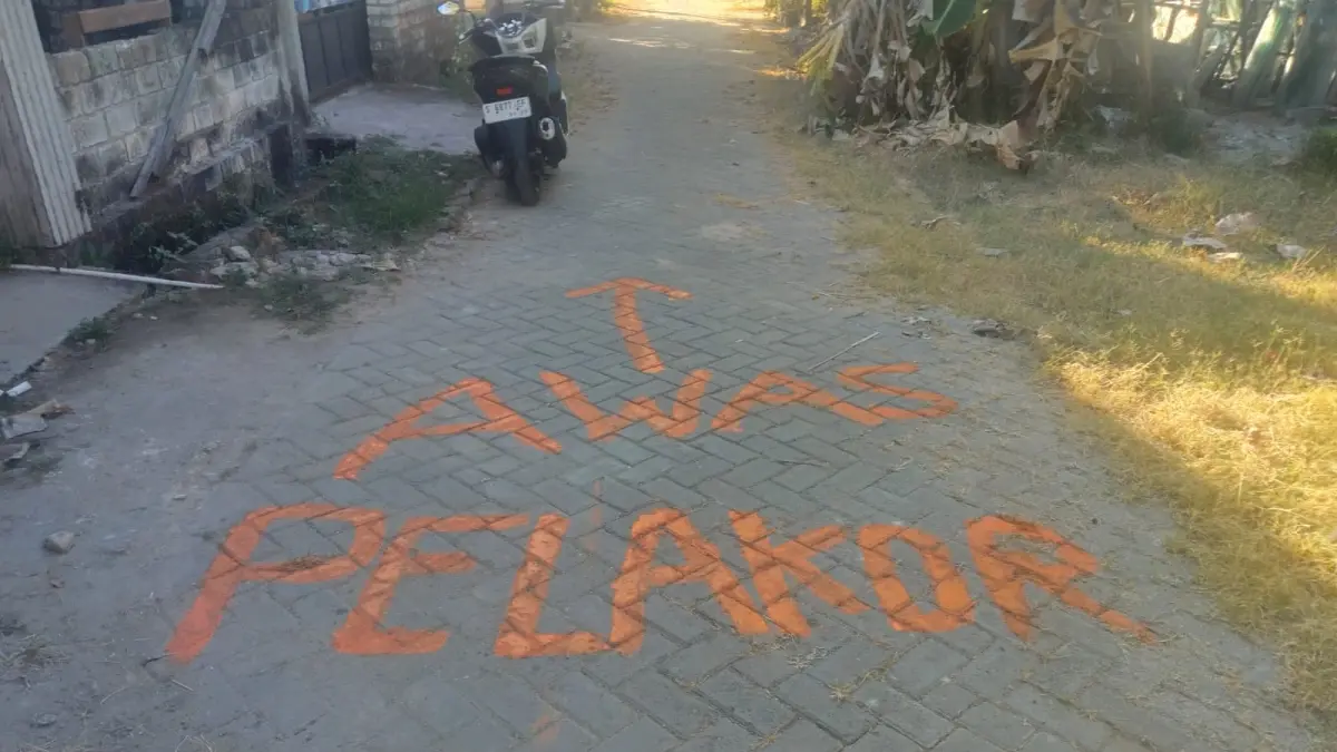 Tulisan Awas Pelakor disertai tanda panah di paving jalan depan rumah terdakwa di Perum Jenggolo Permai Jenu diduga menguatkan unsur pencemaran nama baik terhadap korban. (Andreyan/Radar Tuban)