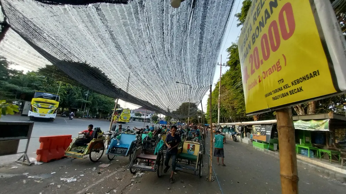 Tukang becak yang mangkal di area Parkir Wisata Kebonsari Tuban yang sepi peziarah Makam Sunan Bonang karena tak banyak bus yang masuk.&nbsp;(Radar Tuban)