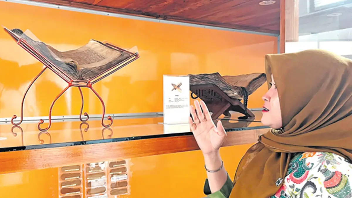 Staf Museum Kambang Putih Tuban menjelaskan keistimewaan mushaf Alquran kuno yang ditulis tangan.&nbsp;(Shafa Dina Hayuning Mentari/Radar Tuban)