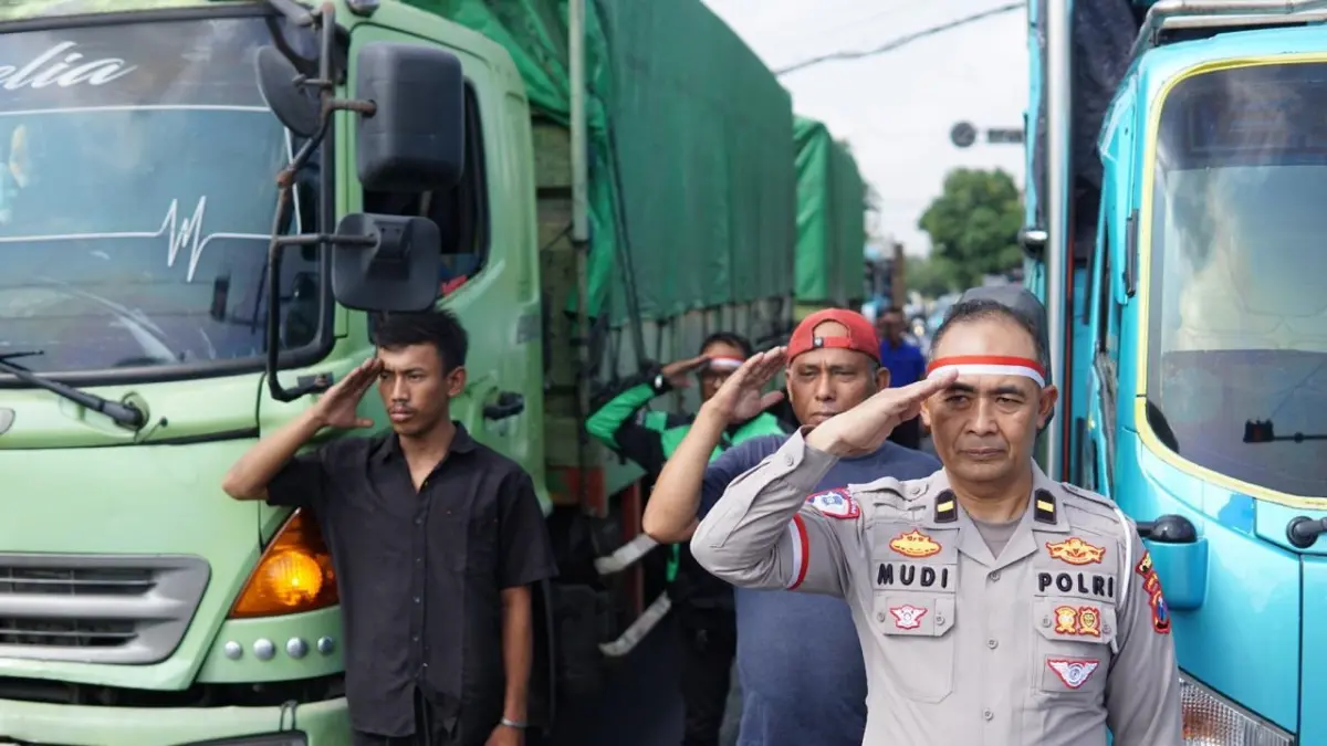 Momen Personel Satlantas Polresta Tuban bersama pengendara di Bundaran Patung Letda Sucipto Tuban melangsungkan penghormatan bendera pada Peringatan Detik-Detik Kemerdekaan RI, kemarin (17/8). (Radar Tuban)