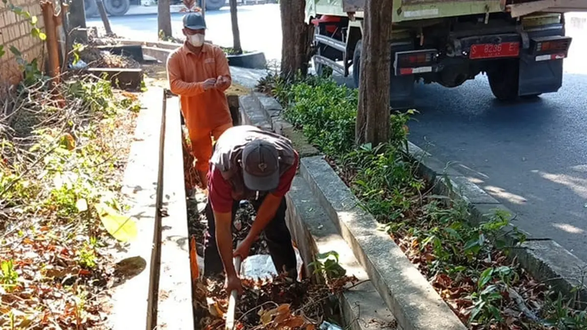 Petugas kebersihan drainase Dinas PUPRPRKP Tuban membersihkan lubang saluran drainase. (DPUPRPRKP TUBAN UNTUK RADAR TUBAN)