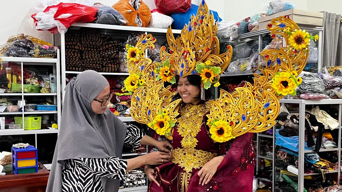 Rini tengah memakaikan salah satu koleksi kostumnya pada seorang pelanggan. (Shafa Dina Hayuning Mentari/ Radar Tuban)