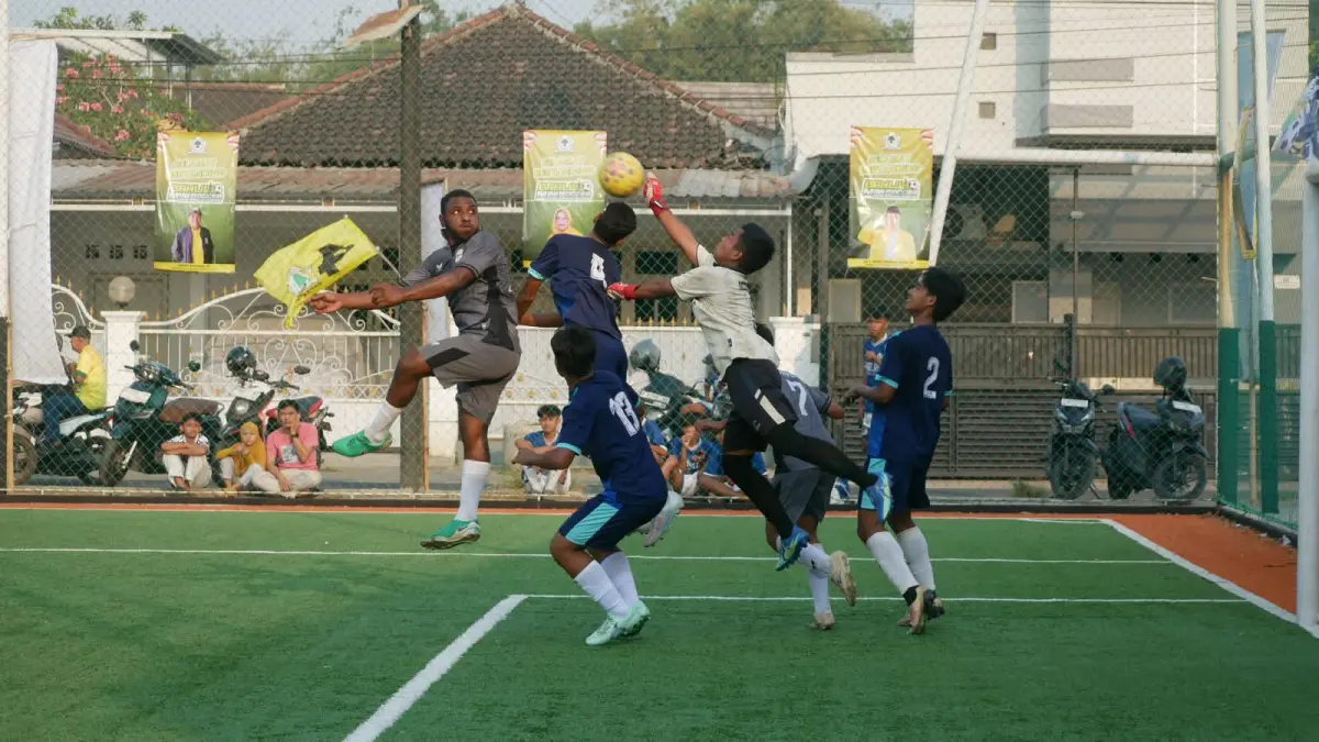 Pemain SMAN Rambipuji Yunus Fefanya Babingga (kiri), berebut bola atas dengan kiper SMKN 2 Jember dalam pertandingan semifinal Bahlil Mini Soccer Zona 10 Jember, Jumat (2/10). Pertandingan itu dimenangkan SMAN Rambipuji dengan skor 2-1. (SIDKIN ALI/RADAR JEMBER)