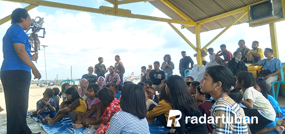 TANAMKAN PESAN MORAL: Teguh Dwi Purwanto mengenalkan tokoh wayang kepada anak-anak di pantai Kelurahan Sidomulyo, Kecamatan Tuban kemarin (20/3). / Yusab Alfa Ziqin