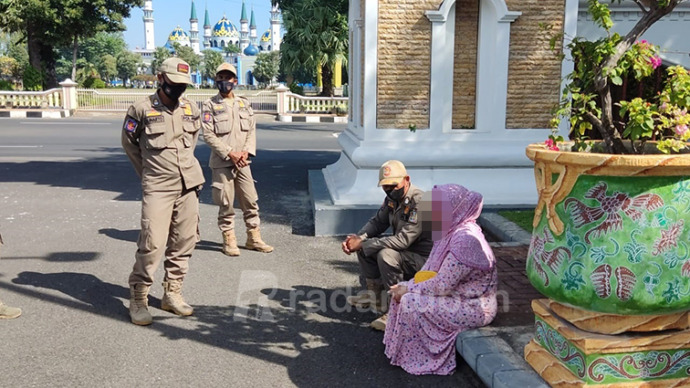 HENDAK KETEMU BUPATI: Petugas piket jaga Satpol PP Tuban saat menenangkan seorang wanita yang kebingungan karena ikut menanggung utang anaknya yang terjerat judi online.