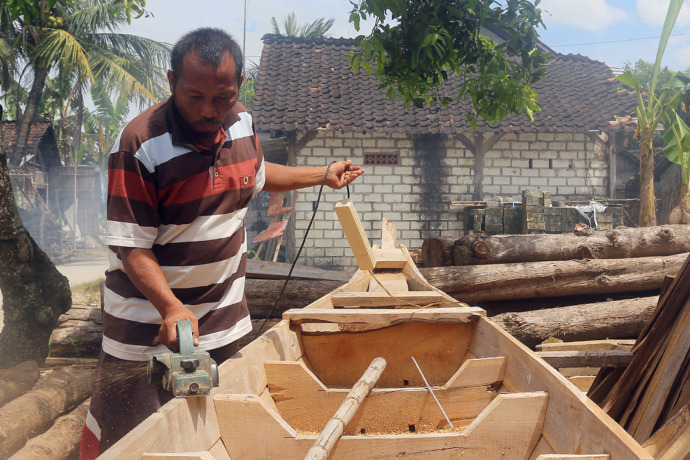 FOKUS: Sujianto berkonsentrasi memoles centhik perahu tembo buatannya menggunakan mesin amplas. (Foto: Yusab Alfa Ziqin/ Radar Tuban)