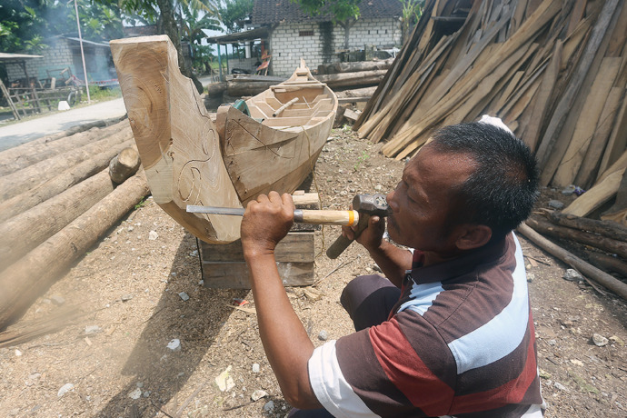 BERI SENTUHAN SENI: Sujianto memahat motif lengkungan di centhik perahu tembo garapannya. (Foto: Yusab Alfa Ziqin/ Radar Tuban
