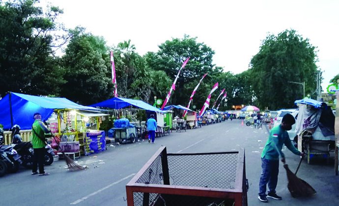 BERSIH-BERSIH: Para petugas kebersihan DLHP Tuban menyapu sampah malam tahun baru di sekitar Alun-Alun Tuban kemarin pagi (1/1). (yusab Alfa Ziqin/Radar Tuban)
