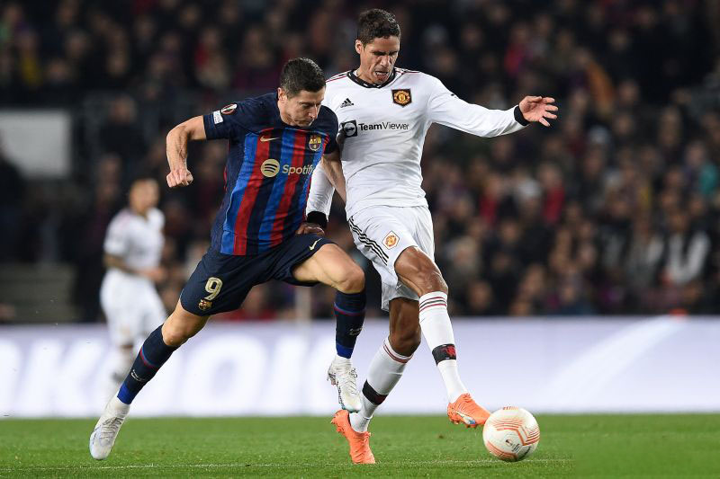 Penyerang Barcelona Robert Lewandowski (kiri) berebut bola dengan bek Manchester United Raphael Varane dalam pertandingan leg pertama babak 32 besar Liga Europa di Camp Nou pada 16 Februari 2023. ANTARA/AFP/JOSEP LAGO