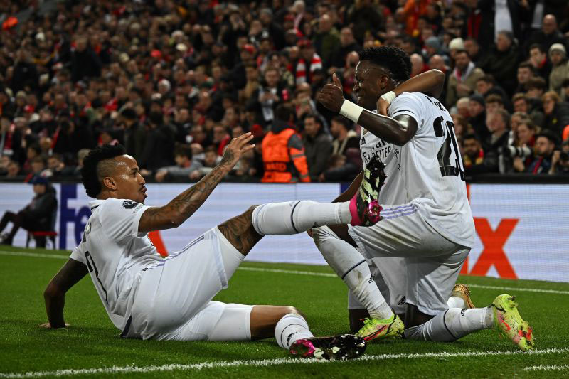 Penyerang Real Madrid Vinicius Junior (kanan) merayakan gol yang dicetaknya ke gawang Liverpool bersama penyerang Real lainnya Rodrygo (tengah) dan bek Eder Militao pada pertandingan leg pertama 16 besar Liga Champions di Stadion Anfield, Liverpool, Rabu