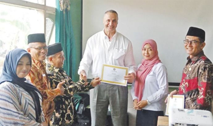 MEMBIMBING NIKAH BULE: Kepala Kemenag Tuban, Ahmad Munir (tiga dari kiri) menyerahkan piagam tanda lulus binwin kepada Ezedin Akari bin Mouhammed Akari dan istrinya pada binwin angkatan XII di kantor KUA Kecamatan Palang kemarin (29/3). (Kemenag Tuban unt