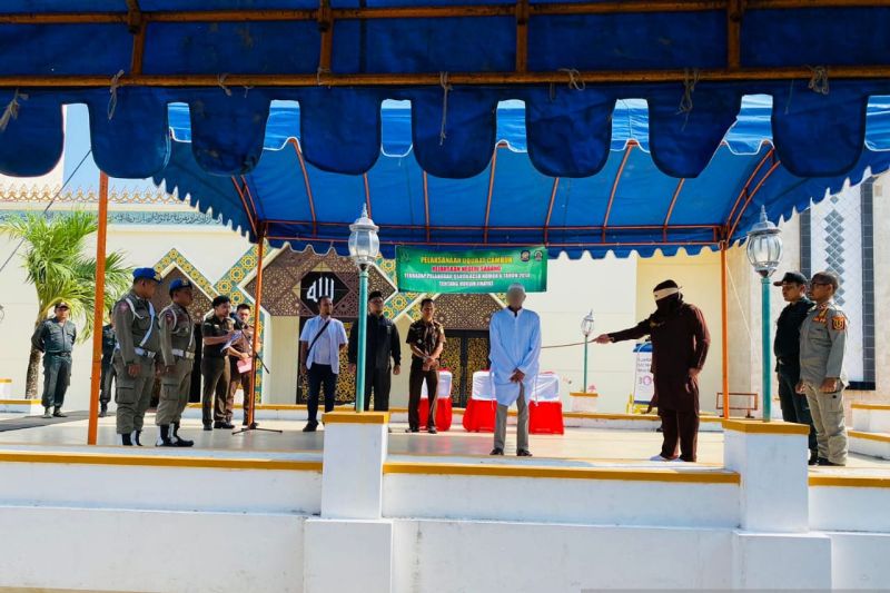 Algojo dari Kejari Sabang melakukan eksekusi hukum 119 kali cambuk terhadap FA yang terbukti melakukan pemerkosaan, di halaman Masjid Agung Babussalam, Rabu (8/3/2023). (ANTARA/HO-Kejari Sabang)