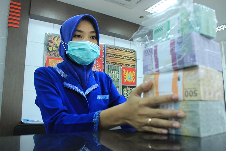 KHAS RAMADAN: Petugas BRI Cabang Tuban saat melayani masyarakat yang menukarkan uang menjelang Idul Fitri. (Yudha Satria Aditama/Radar Tuban)