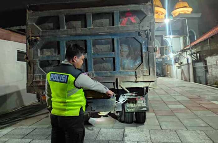 BARANG BUKTI: Anggota Satlantas Polres Pasuruan menunjukkan bokong dump truck yang disundul korban.