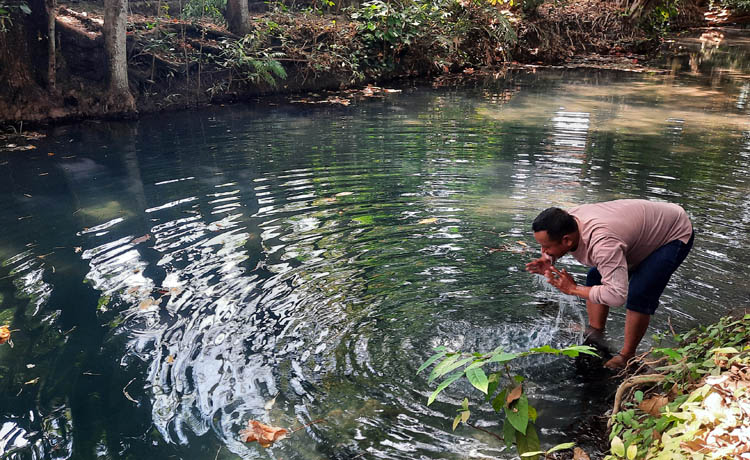 POTENSI DESA: Kasi Pemerintahan Desa Sumberbendo Nurhadi merasakan segarnya air dari sumber mata air Kokap. Pemerintah desa berencana mengolahnya menjadi air minum dalam kemasan. (Foto: Fahrizal Firma