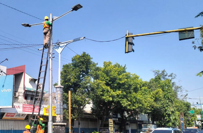 PASANG: Petugas memasang PJU baru di Jalan Panglima Sudirman Kraksaan. (Foto: Agus Faiz Musleh/Jawa Pos Radar Bromo)