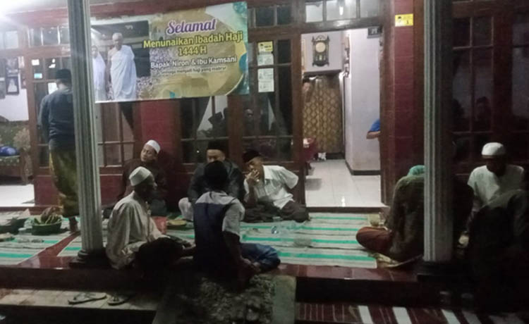 MENGIKHLASKAN: Warga mengikuti tahlilan di rumah Niron di Muneng Kidul, Sumberasih, Selasa (11/7) malam. Nampak poster Niron dan Kamsani istrinya yang terpasang di rumah. (Foto: Istimewa)