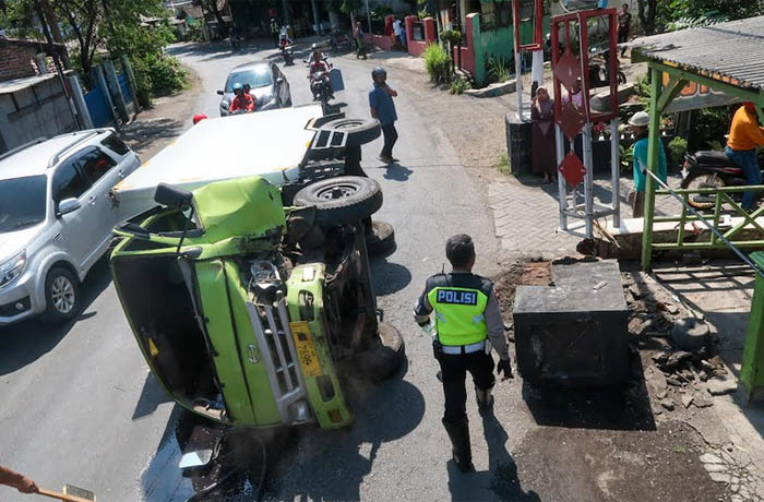 TERGULING: Kondisi truk boks bermuatan ayam frozen terguling di Jalan Urip Sumoharjo, Kelurahan Pohjentrek, Kota Pasuruan, Kamis (27/7) siang. (Mokhamad Zubaidillah/Jawa Pos Radar Bromo)
