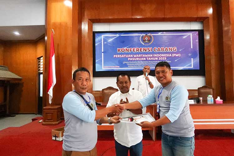 TONGKAT ESTAFET: Ketua PWI Pasuruan 2020-2023 Joko Harianto (kiri) menyerahkan tongkat estafet kepada ketua PWI terpilih Zia Ulhaq disaksikan ketua PWI Jatim Lutfil Hakim (tengah). (Mokhamad Zubaidill