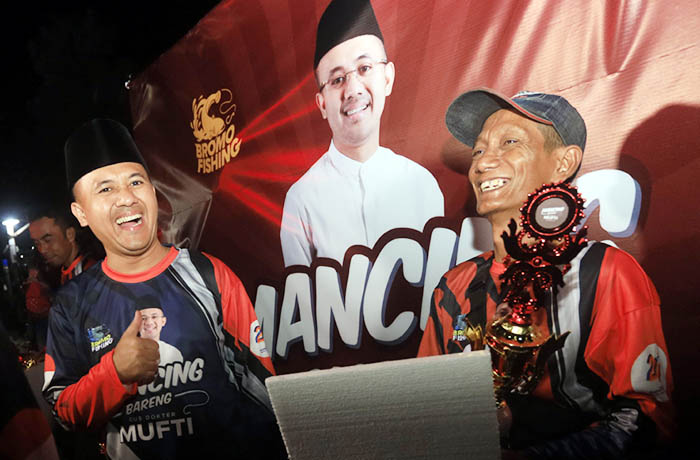SENANG: Hadi yang menjadi pemenang lomba mancing bersama Gus Dokter Mufti.