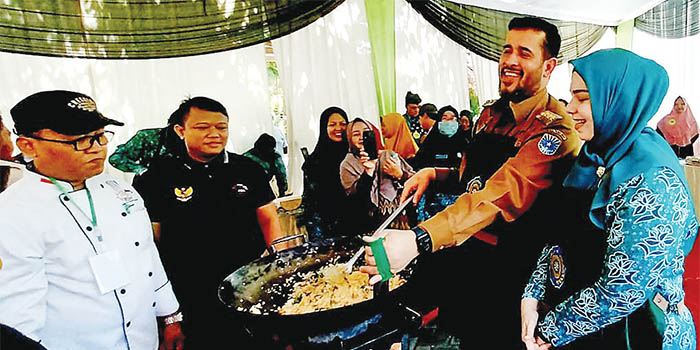 BIKIN NASGOR: Wali Kota Habib Hadi Zainal Abidin didampingi istrinya Hj. Aminah, memasak nasi goreng. Warga pun langsung berebut mencicipinya.