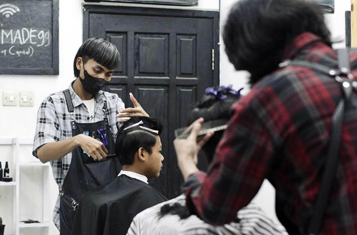 POTONG: Kapster Ecordis Barbershop memotong rambut salah satu pelanggannya. Setidaknya ada sejumlah gaya rambut yang kini diminati.