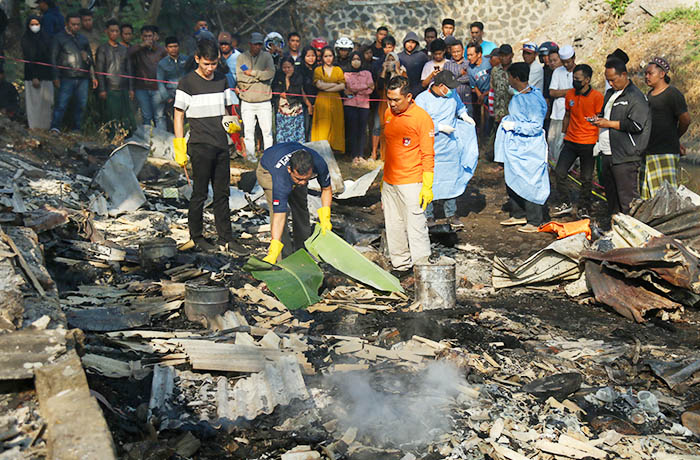 MENINGGAL: Tim Inafis Polres Pasuruan menutup jasad Siti Aisah, 30, penjaga warung di Desa Bakalan, Kecamatan Purwosari, yang meninggal akibat terbakar.