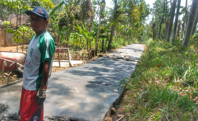 DIBANGUN: Pekerja sedang merabat beton jalan sepanjang 305 meter di RT 19/RW 3, Dusun Wates. Saat ini pembangunan sudah selesai.