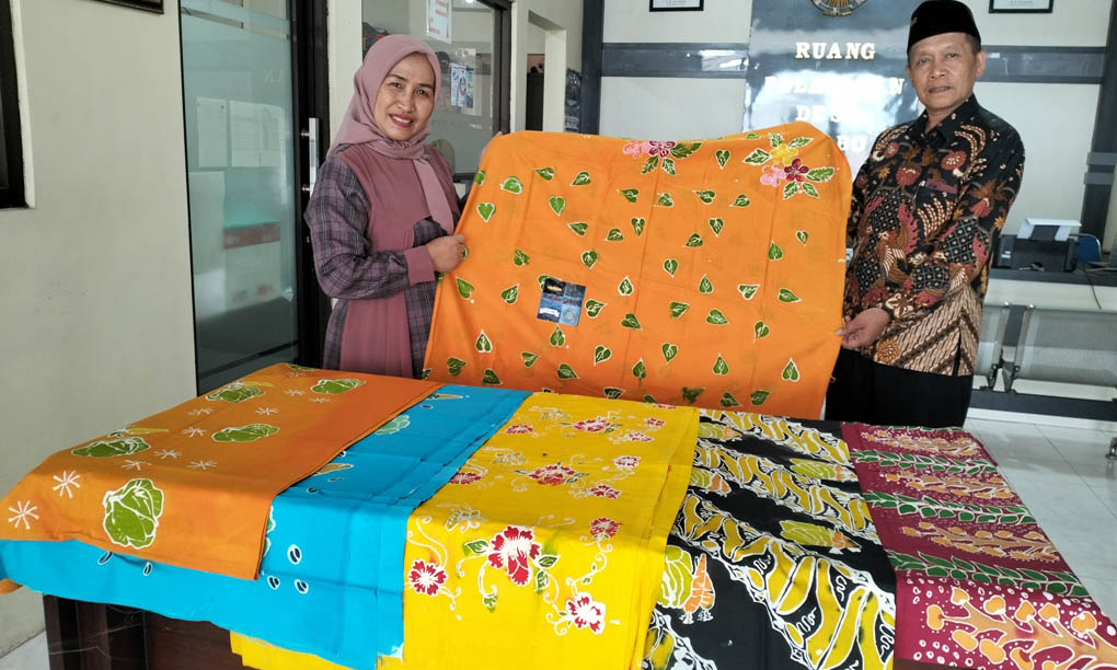 BERAGAM: Kades Gerbo Sutrisno bersama Ketua TP PKK Desa Gerbo Winarni Sutrisno menunjukkan kain batik aneka corak hasil kerajinan remaja dan ibu-ibu di Desa Gerbo.