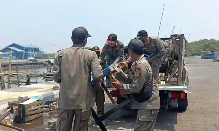 MELANGGAR: Petugas Satpol PP Kota Pasuruan mengangkut 10 gerobak PKL yang ditinggal di kawasan Pelabuhan Pasuruan.