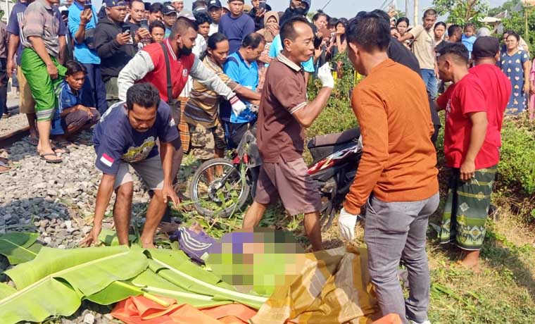 Petugas saat hendak mengevakuasi jenazah korban yang terpental sekitar 5 meter usai keserempet KA Probowangi. (istimewa)