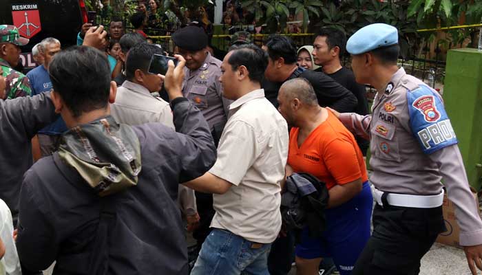 KEMBALI KE RUMAH: Petugas Polres Pasuruan membawa tersangka Khoiri alias Satir, 52, ke rumahnya untuk melakukan rekonstruksi, Kamis (23/11). (Mokhamad Zubaidillah/ Radar Bromo)