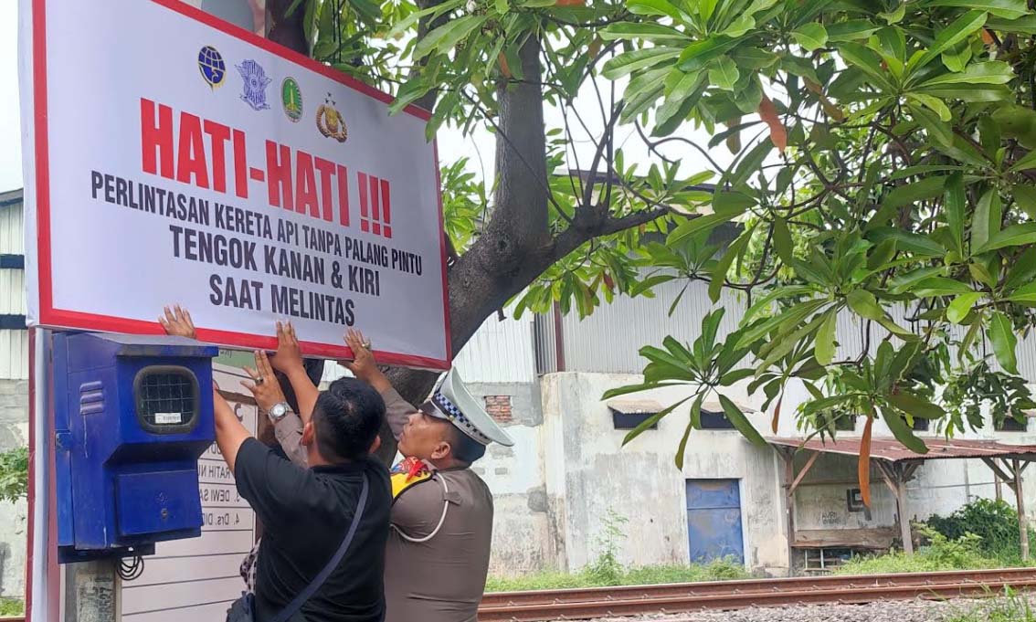 IMBAUAN: Satlantas Polres Pasuruan Kota bersama Dishub Kota Pasuruan memasang spanduk imbauan di perlintasan KA tanpa palang pintu.