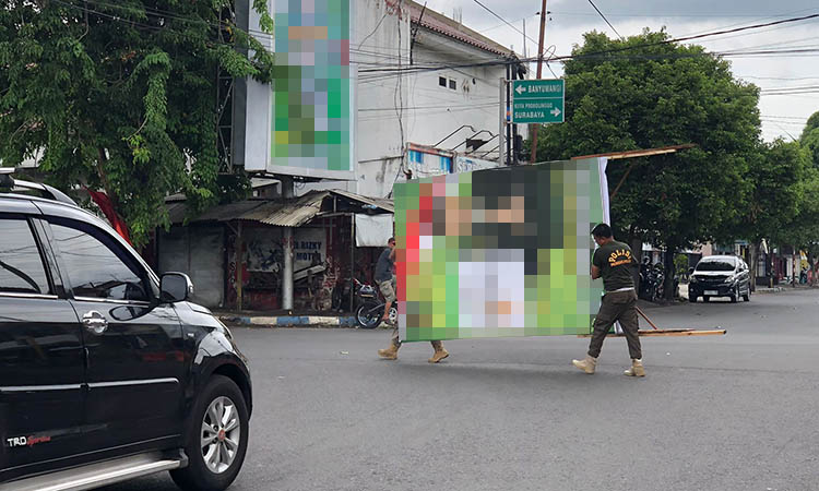 TURUNKAN APK: Petugas Satpol PP Kota Probolinggo saat melakukan penertiban APK di simpang empat antara Jalan Ahmad Yani dan Jalan dr. Sutomo, Mayangan, Kota Probolinggo, Jumat (19/1).