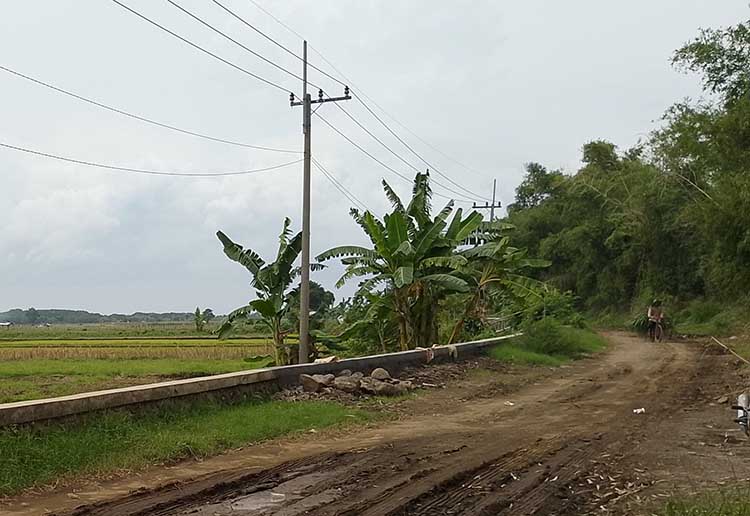 RAMPUNG: Seorang warga melintas di jalan yang TPT sebelumnya rusak diterpa banjir. Kini, TPT itu sudah rampung dibangun.