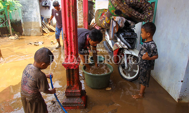 BERSIH-BERSIH: Warga di Dusun Jetis, Desa Prodo, Kecamatan Winongan, Kabupaten Pasuruan membersihkan lumpur di rumah masing-masing setelah banjir bandang yang mener