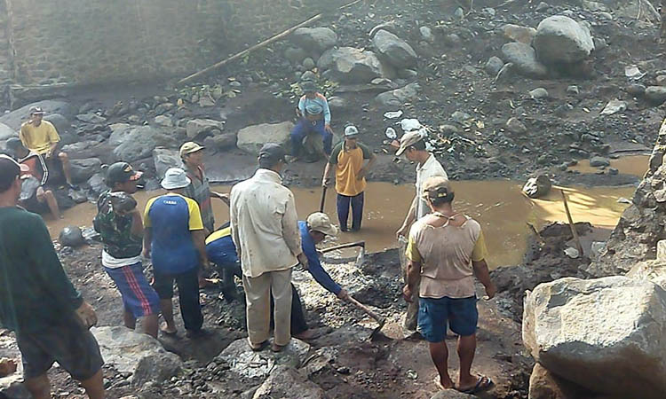 KERJA BAKTI: Warga Desa/Kecamatan Lumbang, Kabupaten Pasuruan kerja bakti mengevakuasi batu-batu besar yang menutup lokasi bekas jembatan yang hanyut terbawa banjir bandang.