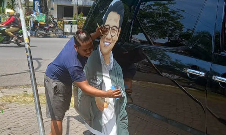 MEMOTONG: Irul memasang dan memotong stiker kendaraan pribadi dengan gambar berbeda.