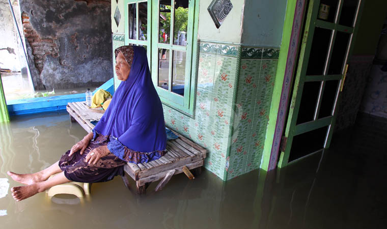 LUMPUH: Warga Dusun Balongrejo RT 29 RW 9 Desa Kedungringin, Kecamatan Beji duduk diteras rumahnya yang terendam banjir.